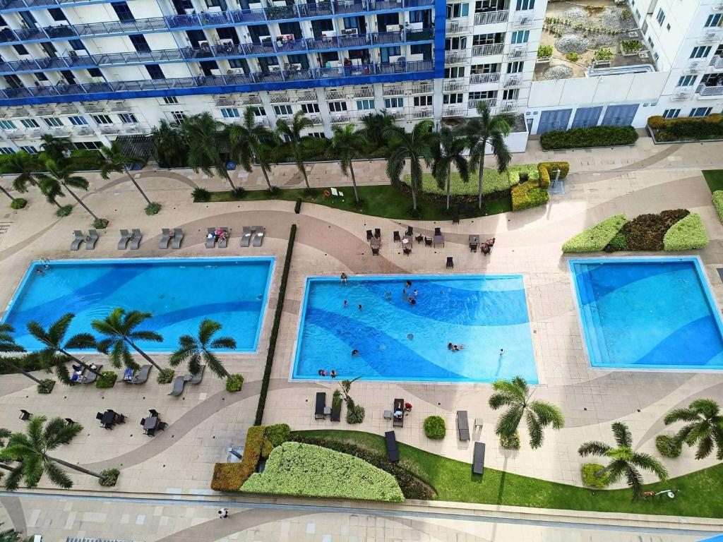 einen Blick über den Pool in einem Gebäude mit Palmen in der Unterkunft Sea Residences Wonders in Manila