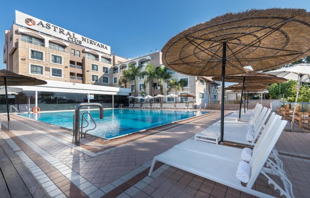 ein Swimmingpool mit Stühlen und einem Sonnenschirm in der Unterkunft Hotel Astral Nirvana Club- Half Board in Eilat