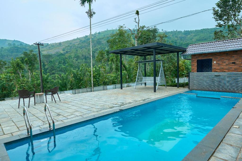 een zwembad met een picknicktafel en een parasol bij Sylora Meadows Private Pool Villa ,Vagamon in Pīrmed