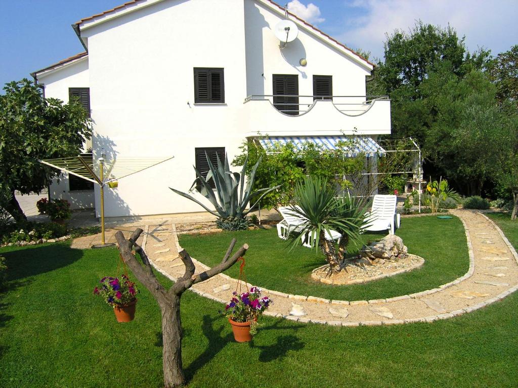 a white house with a yard with plants at Apartmani Dolencic in Krk