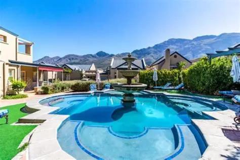 een groot zwembad met een fontein in een tuin bij L'Ermitage Villa Francois in Franschhoek