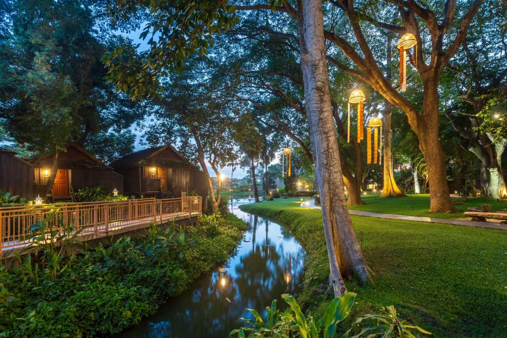 a river with trees and huts in a park at night at Lampang River Retreat in Lampang