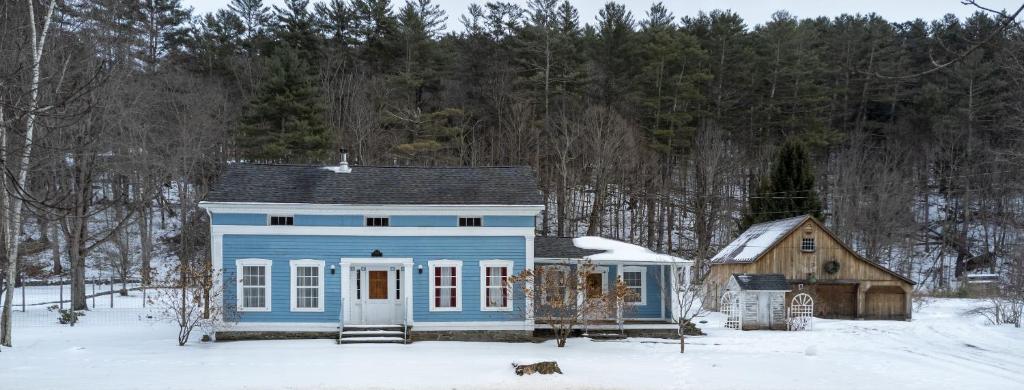 een blauw huis in de sneeuw met een hond ervoor bij The Tannery House in Claryville