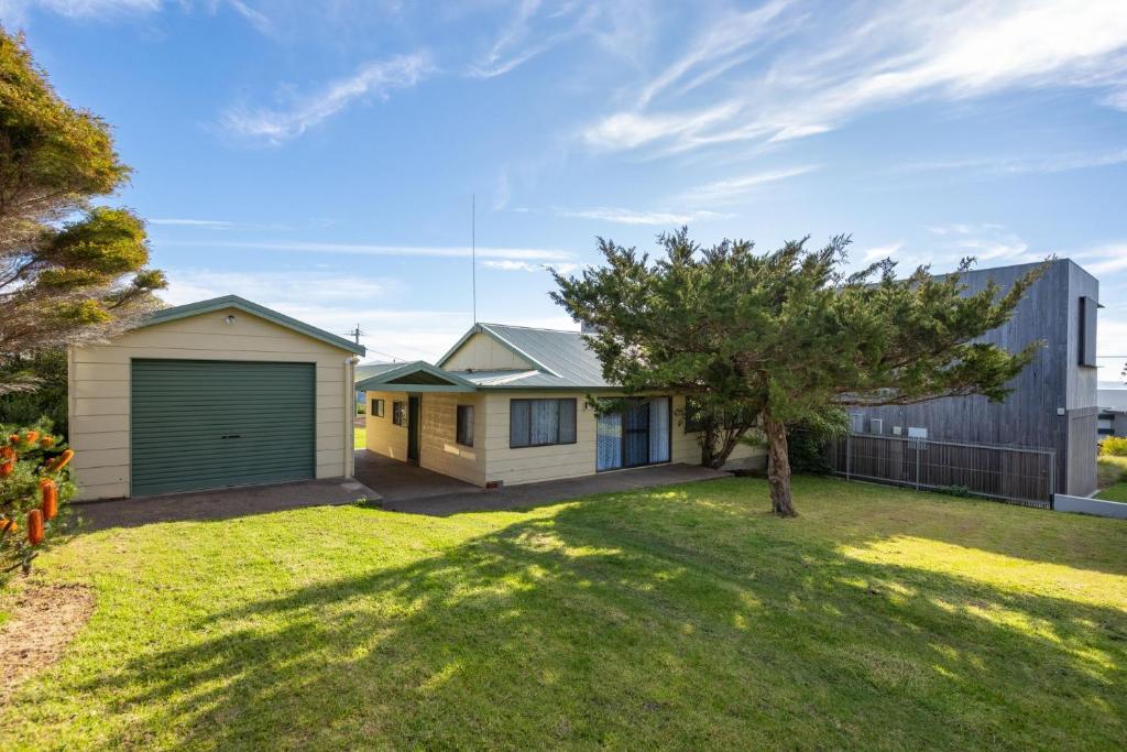 een huis met een garage in een tuin bij 3 Barragoot Street in Bermagui