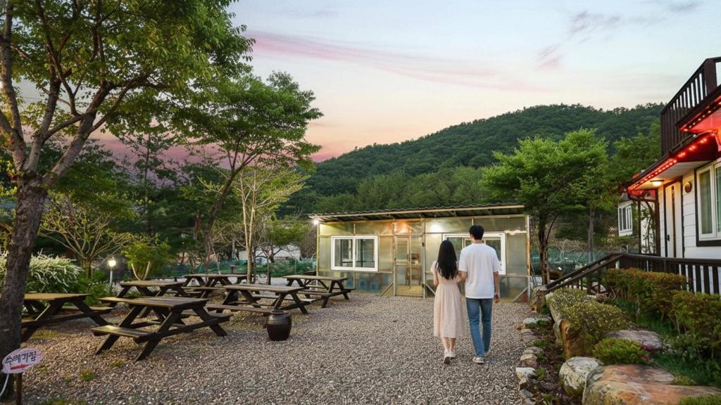 ein Mann und eine Frau gehen außerhalb eines Gebäudes in der Unterkunft Samcheok Duelkkot Pension in Samcheok