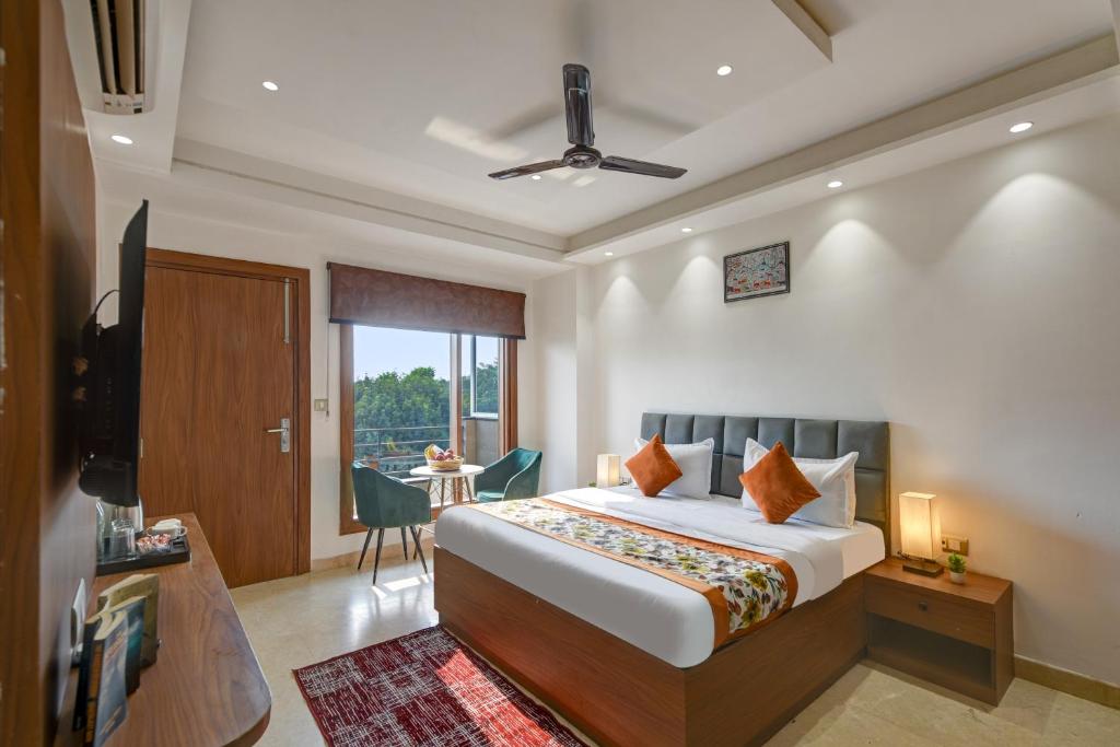 a bedroom with a bed and a television and a table at Qotel Comfort Ashok Vihar in New Delhi