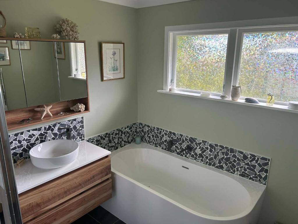 ein Badezimmer mit Badewanne und Waschbecken und einem Fenster in der Unterkunft Beachy Sounds House in Carters Beach