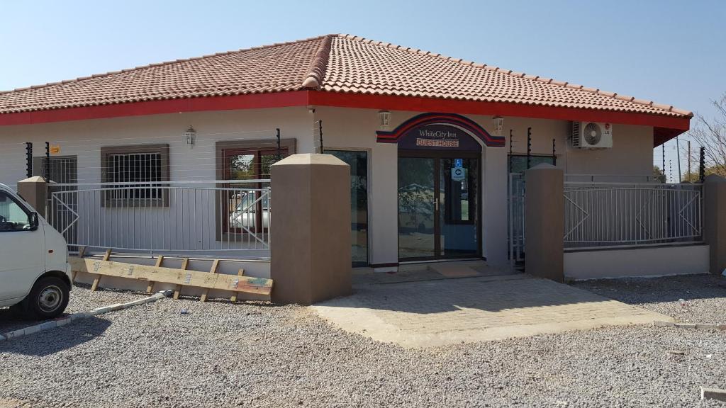 ein Gebäude mit einem davor geparkt in der Unterkunft White City Inn in Gaborone