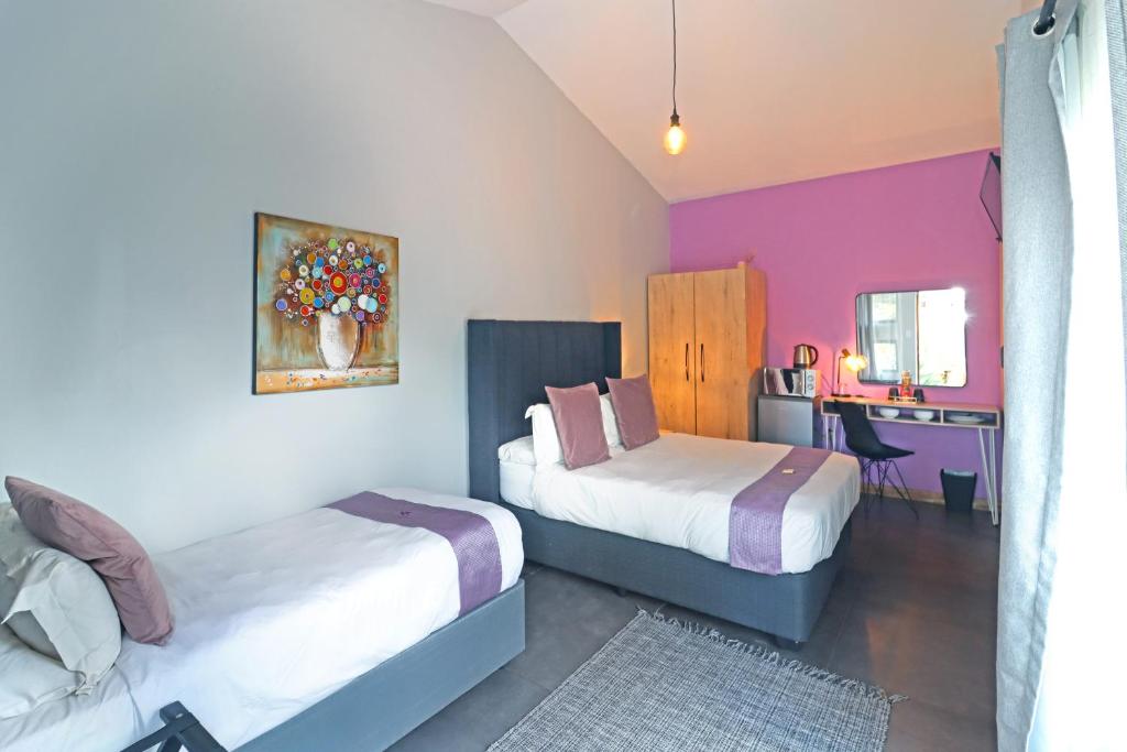 een hotelkamer met twee bedden en een bureau bij The Chameleon Stay @107 in Centurion