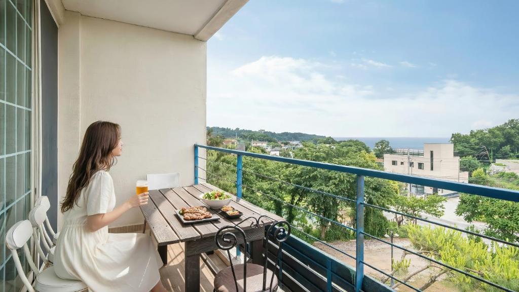 een vrouw op een balkon met een tafel met eten bij Ganghwado Happyvilly Pension in Incheon