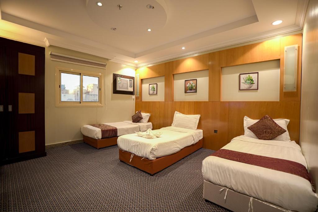 een hotelkamer met twee bedden en een raam bij فندق المغاربي للشقق الفندقية 3 in Al Madinah