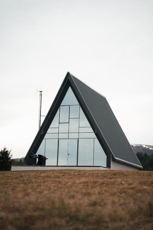 a building with a triangular roof on top of a field at The Sky Hill - luxury chalet in Kupres
