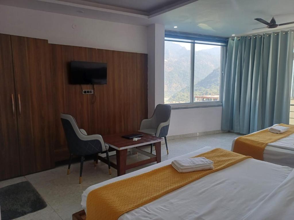 een hotelkamer met twee bedden, een bureau en een televisie bij The JRS Hotel in Rishīkesh