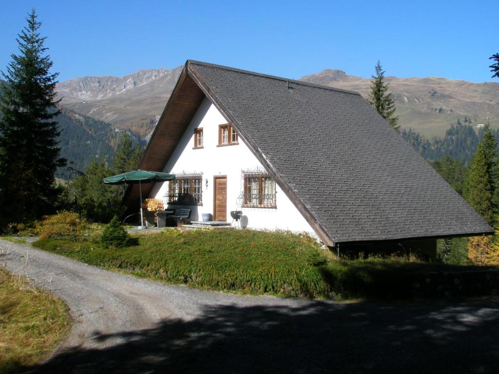 a white house with a black roof on a road at Chalet Atelier in Davos