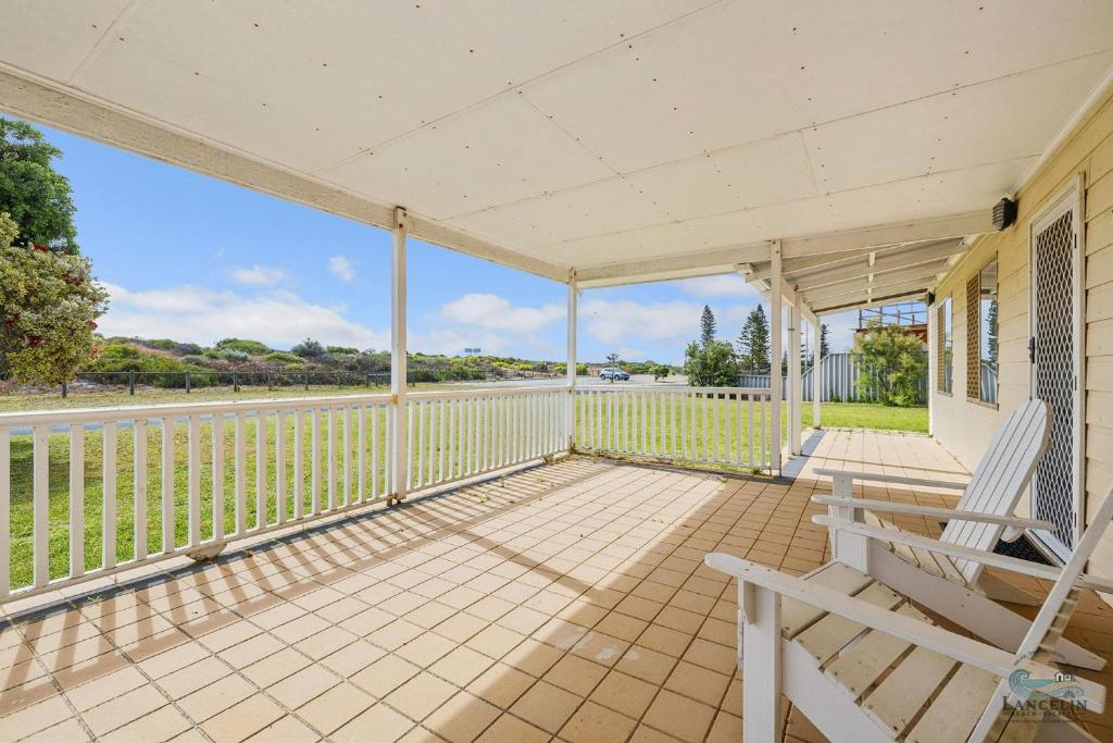 an empty porch with a bench and a fence at Packem Inn in Lancelin