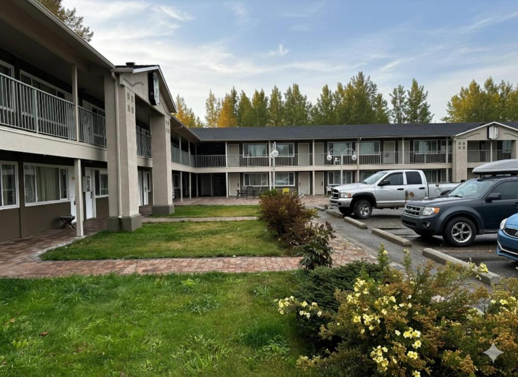 a building with cars parked in a parking lot at Quesnel Inn in Quesnel