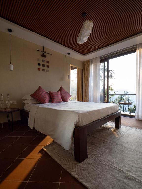 a bedroom with a large bed and a large window at Deoja Forest Stay in Darjeeling