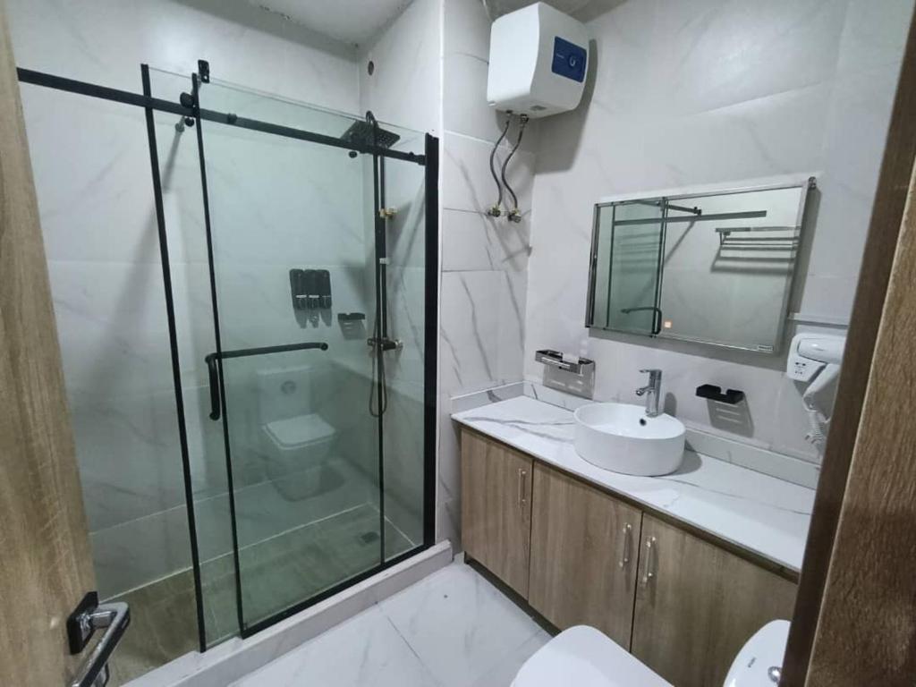 a bathroom with a glass shower and a sink at Immaculate Excellence Luxury Hotels Ltd in Owerri