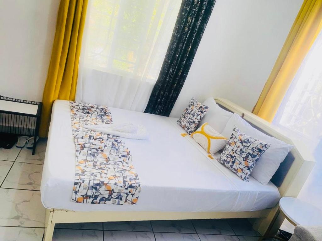 een wit bed in een kamer met een raam bij Tash Studios in Diani Beach