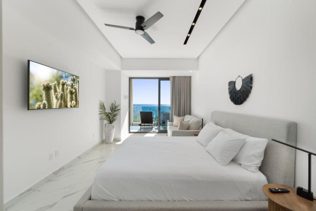 a white bedroom with a bed and a couch at Encantame Soleil New Resort 3rd Floor Studio in Playa Encanto