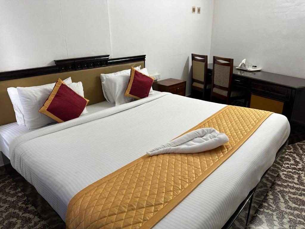 a hotel room with a large white bed with a towel on it at Pournami Inn in Chengannūr