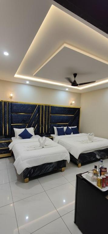 a bedroom with two beds with blue pillows at Hotel Haven Suite in Lahore