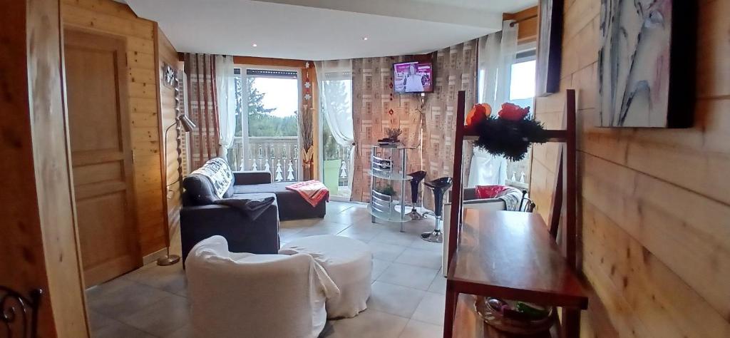 a living room with white chairs and a table at Appartement les Coquelicots Super Besse in Besse-et-Saint-Anastaise