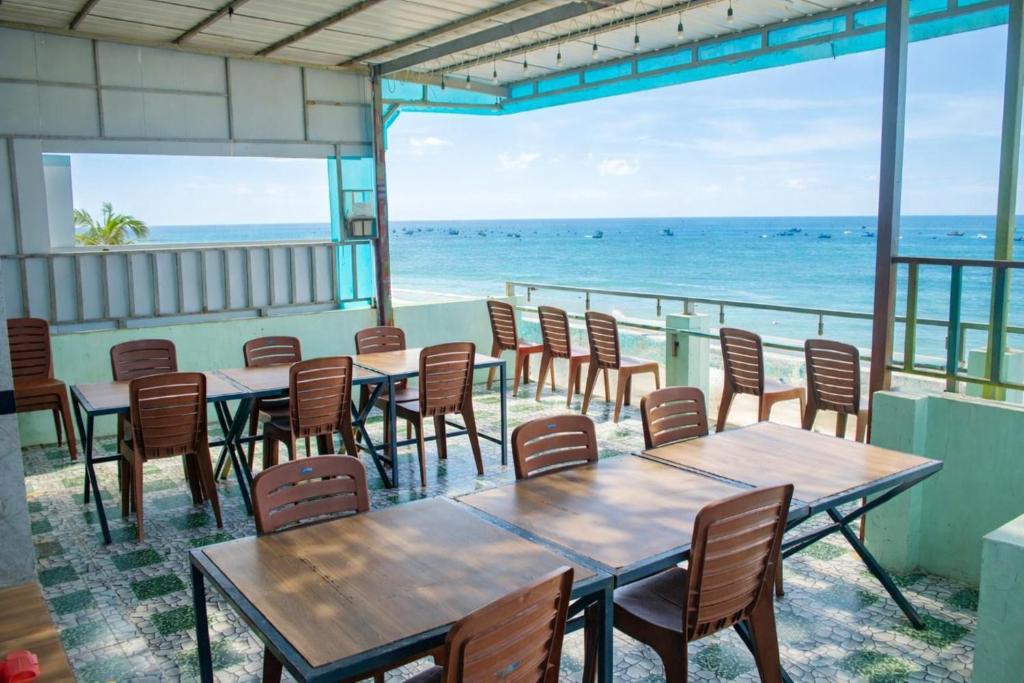 a restaurant with tables and chairs and the ocean at Hoàng Thiện Homestay đảo Phú Qúy in Cu Lao Thu