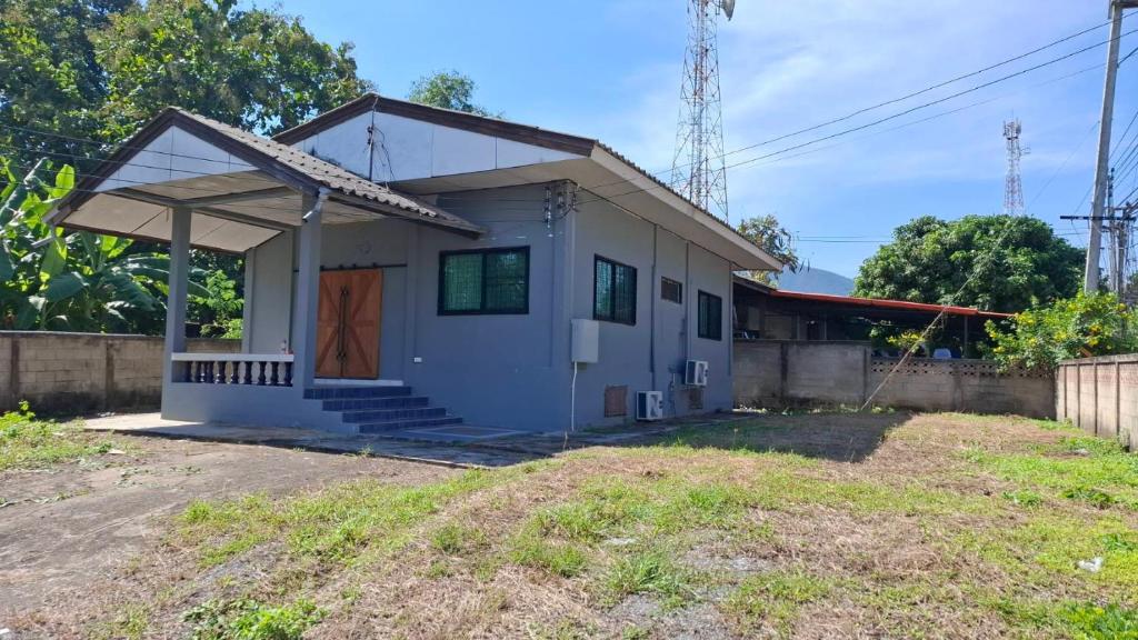 una piccola casa bianca con una porta marrone di Banpakan homestay 