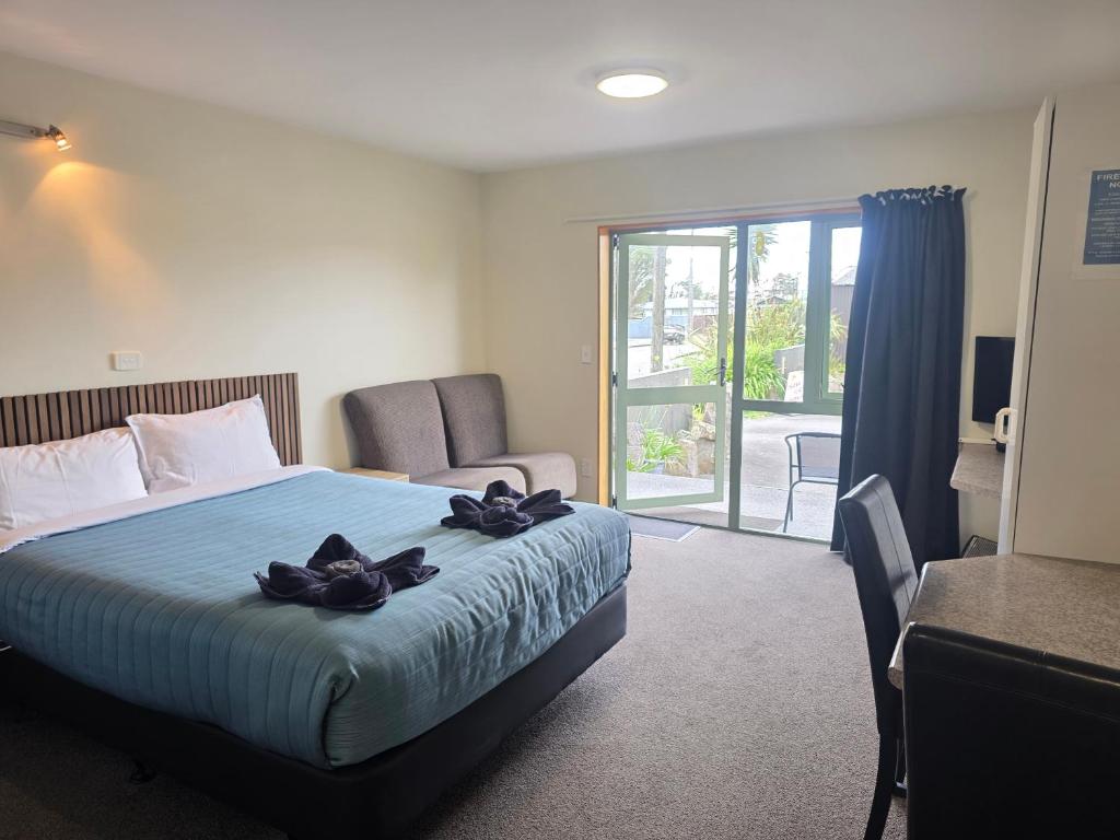 ein Hotelzimmer mit einem Bett und einer Glasschiebetür in der Unterkunft Palmcourt Motel in Westport