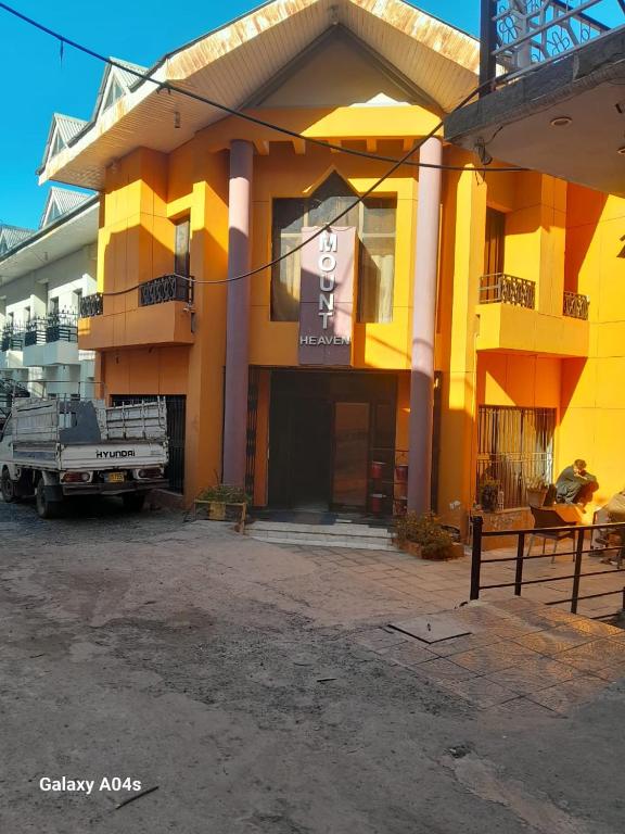 a yellow building with a truck parked in front of it at Hotel Mount Heaven in Murree