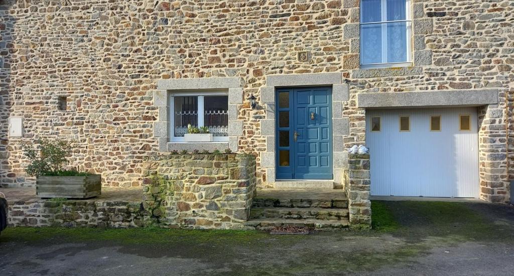 een bakstenen gebouw met een witte garage en een blauwe deur bij Chambre D'hôtes De La Gandonnière in La Duchaie