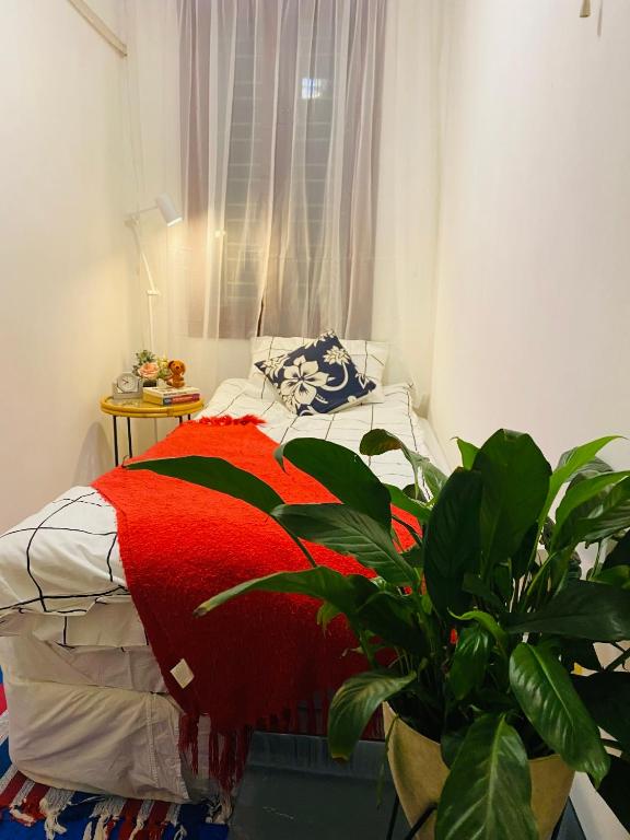a bedroom with a bed with a red blanket and a plant at L'e'tage House in Hanoi