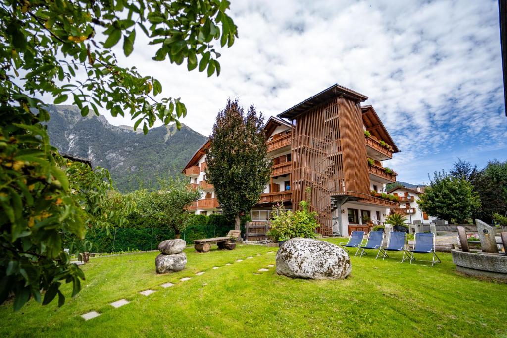 a building with chairs in the grass in front of it at Hotel Orso Grigio in Carisolo