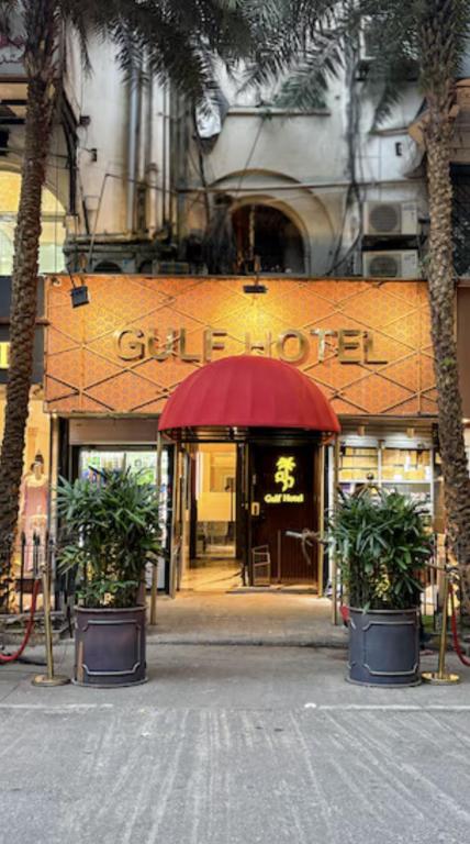 a store front with a red umbrella and palm trees at Gulf Hotel Mumbai- The Boutique Hotel Colaba Mumbai in Mumbai