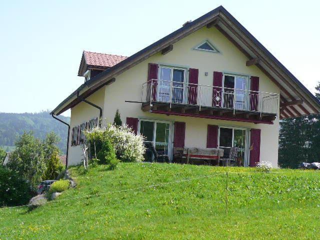 a house on top of a grassy hill at Ferienwohnung Bio-Bauernhof Schuwerk in Isny im Allgäu