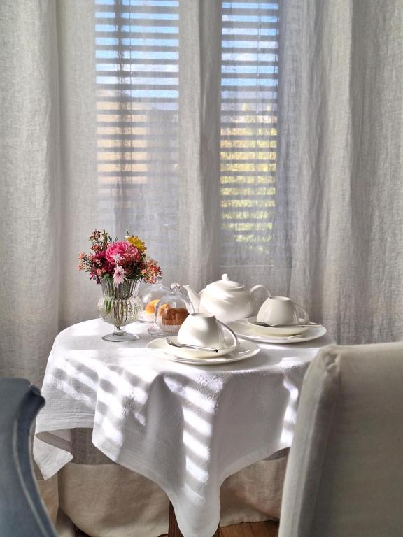 einen Tisch mit einem weißen Tischtuch und Blumen darauf in der Unterkunft al piccolo giardino in Vittorio Veneto