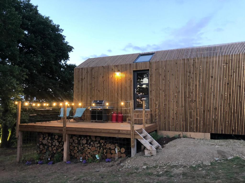 a small building with a deck with lights on it at Domaine de Hurlevent - Tiny House petite maison écologique in Aywaille