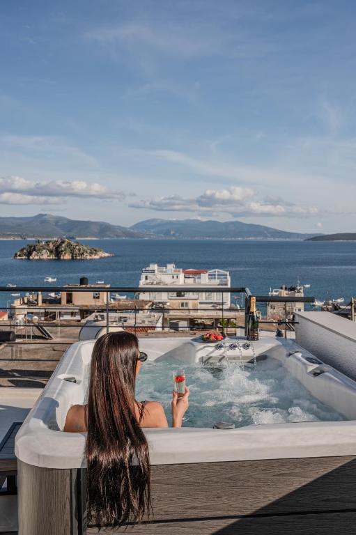 a woman sitting in a bath tub with a drink at Noma Suites Tolo in Tolo