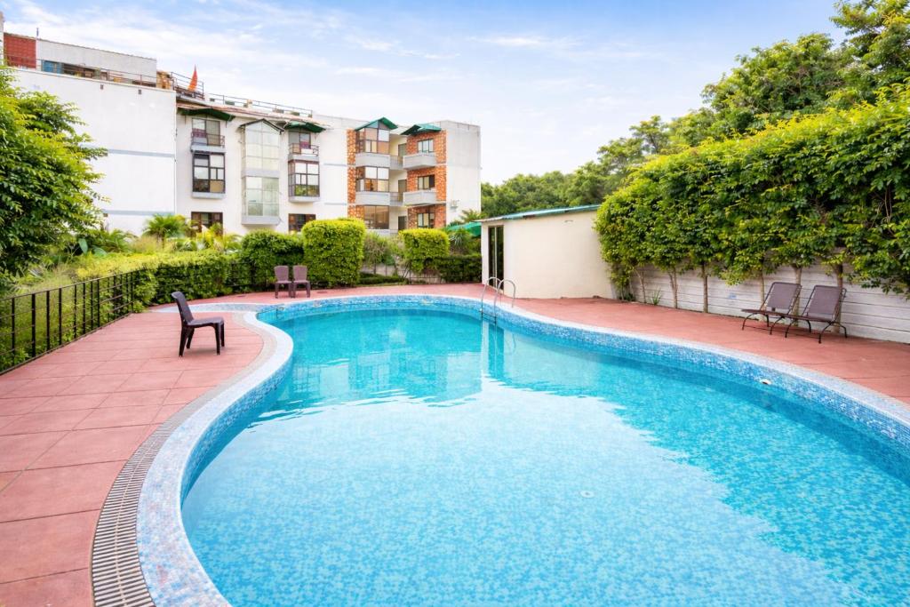 a swimming pool with a chair and a building at Shelton Blu Resort By Mango People in Rāmnagar