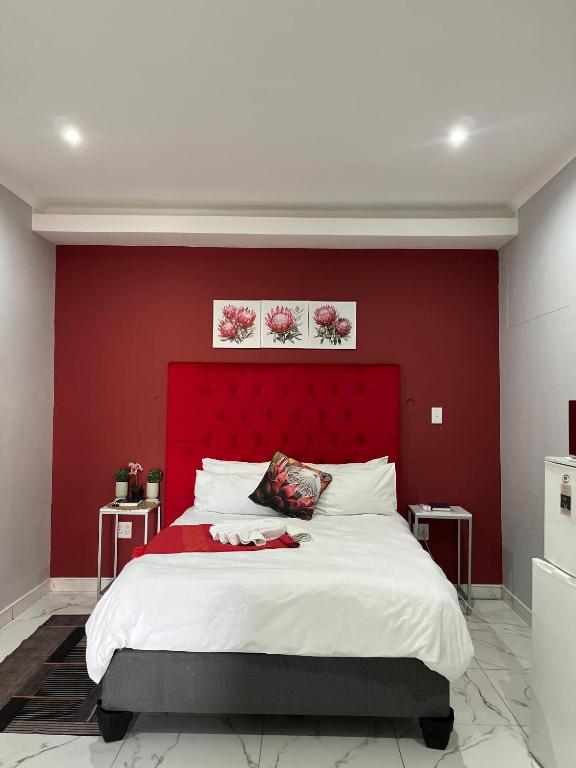 a bedroom with a large bed with a red headboard at Red Hills Guesthouse in Tsumeb