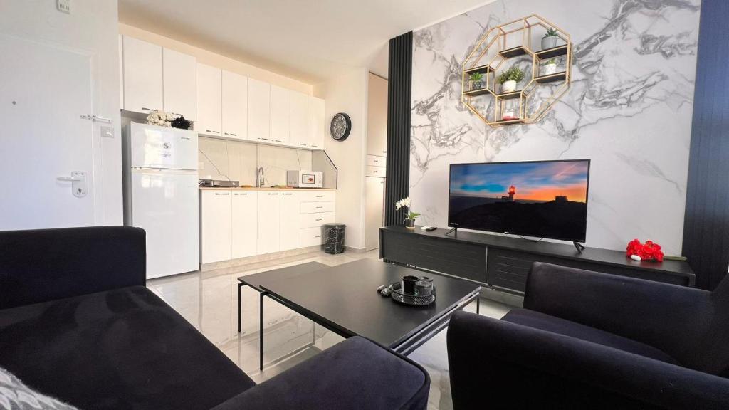 a living room with a table and a tv on a wall at דירת 2 חדרים בטיילת בת ים in Bat Yam
