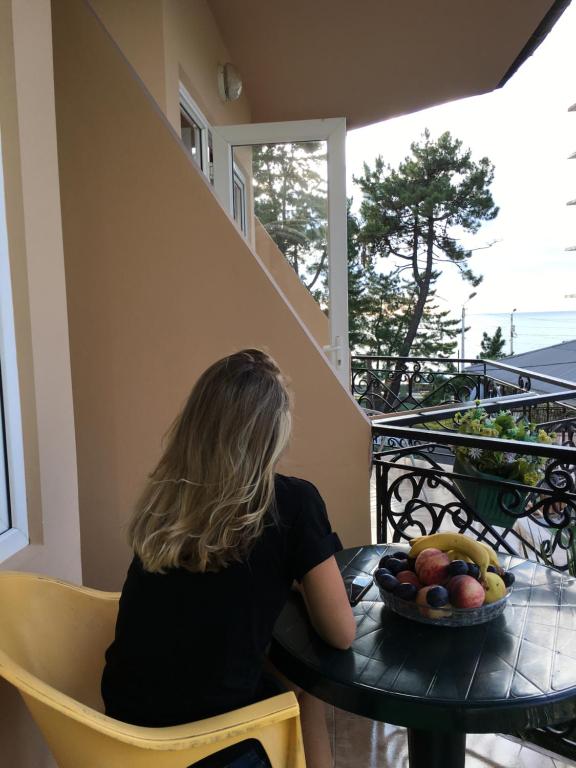 Una donna seduta a un tavolo con un cesto di frutta di Hotel Simpatia a Kobuleti
