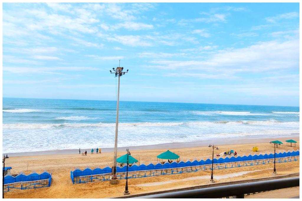 a beach with blue chairs and umbrellas and the ocean at Hotel Seabeachdreamland Heights Near jagannath Temple - Restaurant & Parking - Fully Air Conditioning Rooms - Best Hotel in Puri