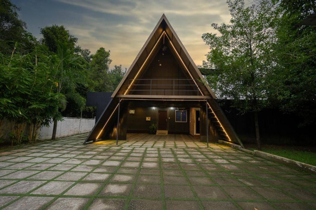 ein Haus mit einem dreieckigen Dach und einer Terrasse in der Unterkunft River Serene Holiday home in Kizhake Chālakudi