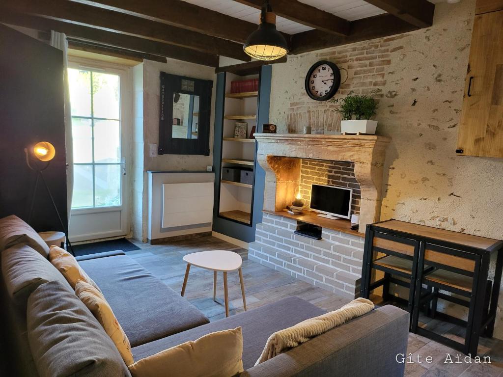 un soggiorno con divano e camino di Le Gite Aïdan a La Puye