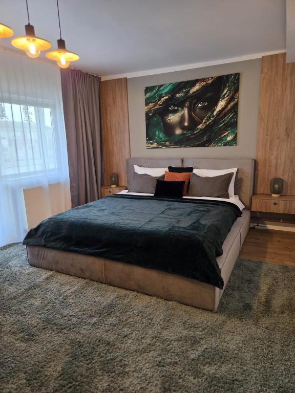 a bedroom with a large bed with a large painting on the wall at ALiVA Stay Apartment in Craiova