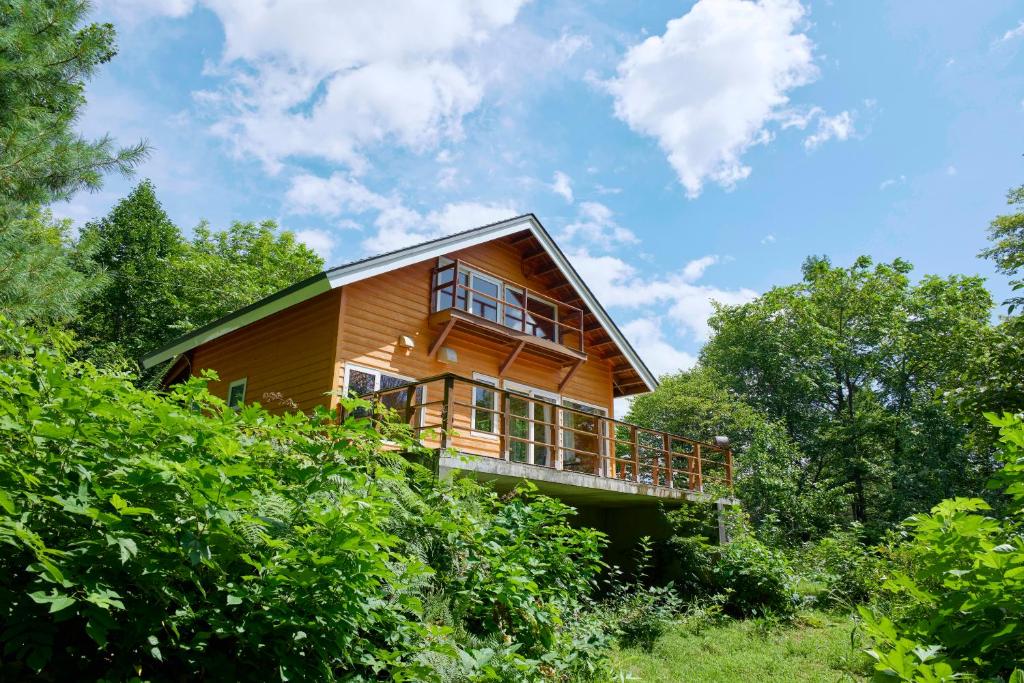 a wooden house with a balcony in the trees at Tokachi Mikage forest villa in Mikage