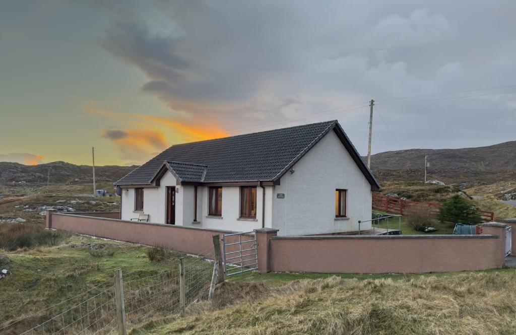 ein Haus auf einem Hügel mit Regenbogen im Hintergrund in der Unterkunft Tamh Cottage in Tarbert