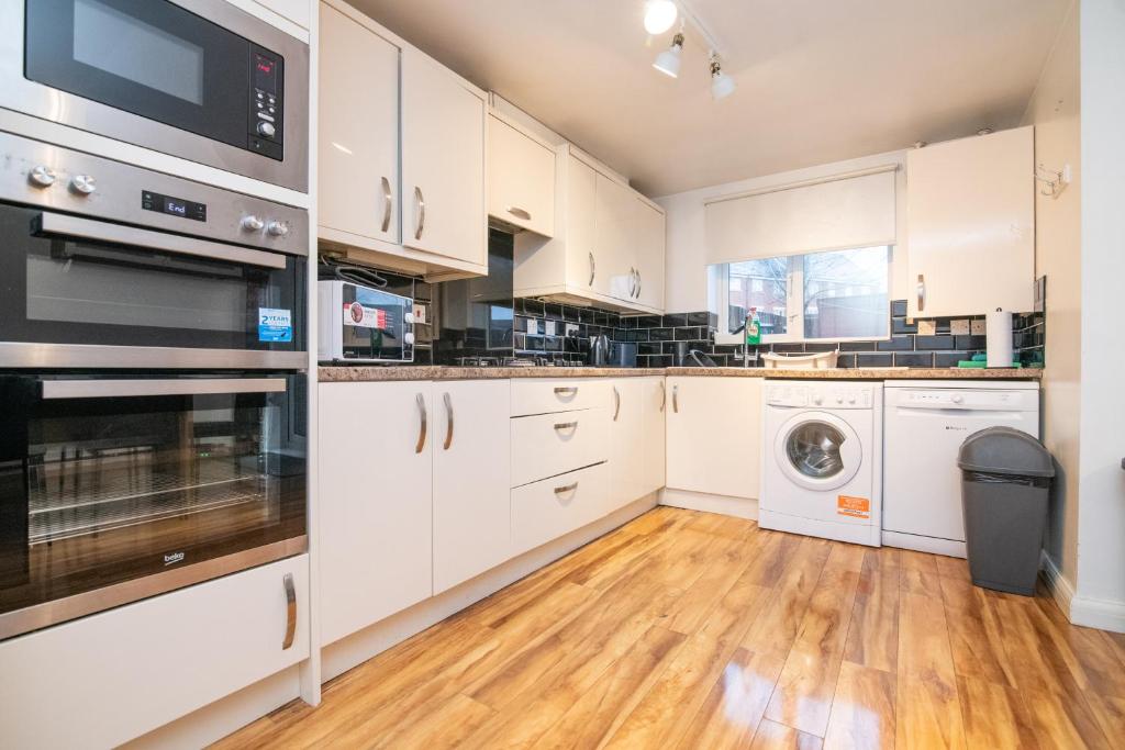 eine Küche mit weißen Schränken und einer Waschmaschine und einem Trockner in der Unterkunft 5 bed house with free secure parking in pleasant quiet location in Wolverhampton